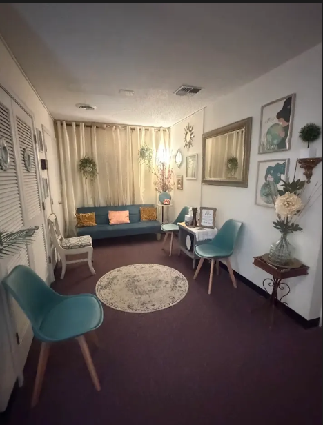 Quiet seating area with a teal sofa, framed art, and soft lamp light