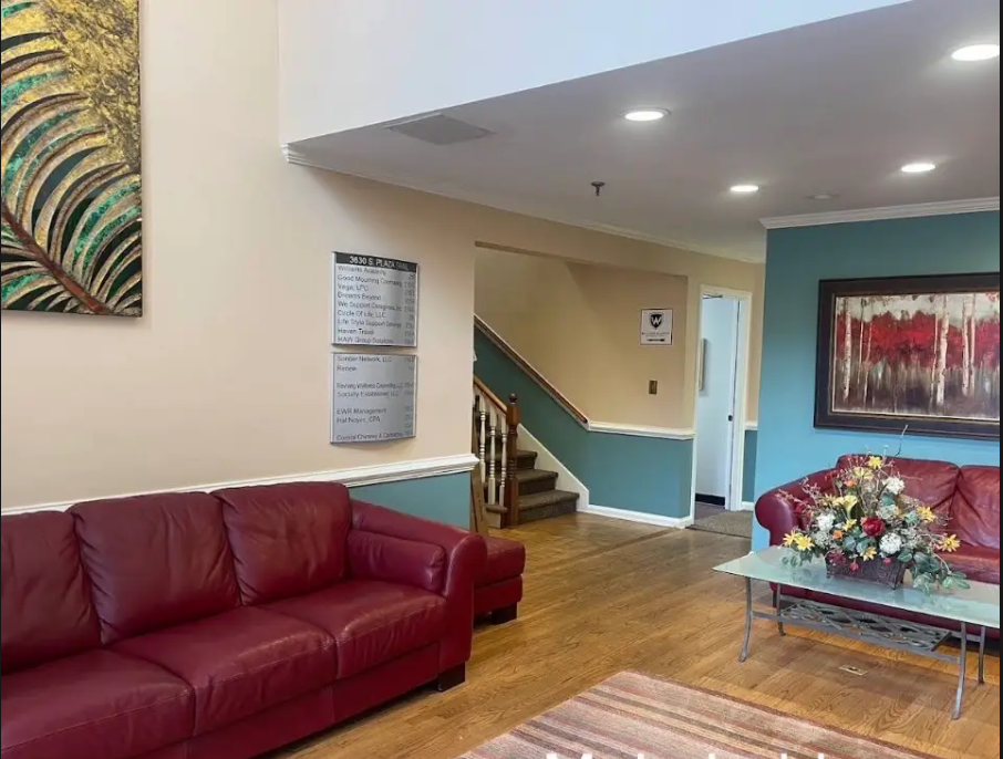 Main lobby with red leather sofas, hardwood floors, and the building directory by the stairs